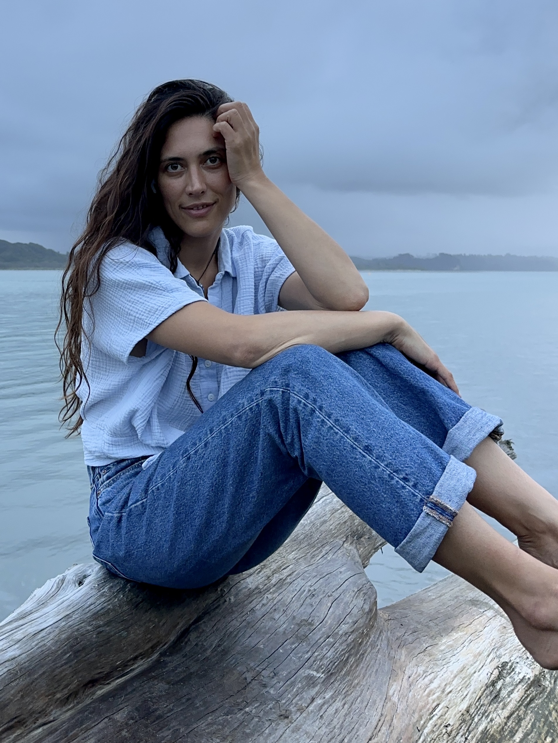 Aschel Gregory seated on driftwood near the water